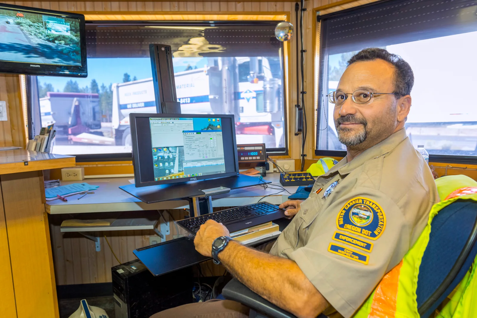 An Oregon transportation employee working at a desk inside a truck weigh station, July 2019